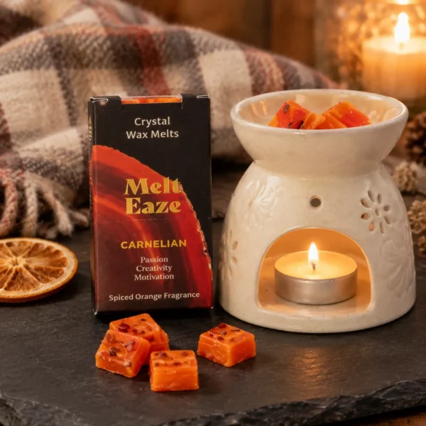Zwart Melt Eaze doosje met carneool wax melts naast losse oranje blokjes met stukjes carneool en een witte oliebrander met waxinelichtje